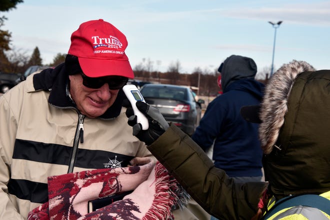 A supporter has his temperature taken as he arrives to see President Donald Trump at a campaign rally in Traverse City, Mich. Monday, Nov. 2, 2020.