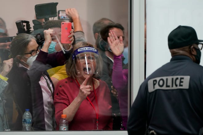 Election challengers yell as they look through the windows of the central counting board as police were helping to keep additional challengers from entering due to overcrowding at TCF Center in Detroit, Wednesday, Nov. 4, 2020.