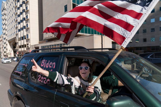 A Biden supporter cheers while driving past a Trump rally protesting the election results after Democrat Joe Biden was declared the winner Saturday, Nov. 7, 2020, at the State Capitol in Lansing, Mich.