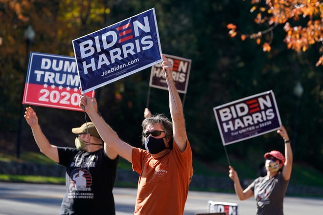 Supporters of President-elect Joe Biden wave signs at the entrance to Trump National golf club in Sterling, Va., Saturday Nov 7, 2020. Trump was at the facility.