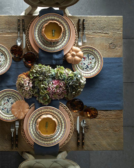 The hand-painted pattern on glazed earthenware made in Portugal is based on a typical Portuguese design from the 19th century. A blue linen table runner set on a rustic wood table keeps it simple. The ceramic pumpkin tureen pairs well; you can also sub a real heirloom pumpkin in sage, apricot or cream as a container for soup. The Pavoes dinnerware is available at Neiman Marcus.