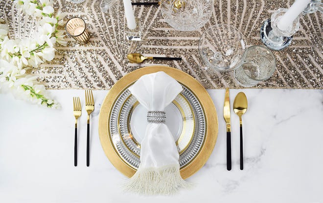 A little glitter lends luxe to the table. A Deco-inspired sequins table runner sets the stage and there's plenty of gold in plates, flatware, with jewelry accents like the rhinestone napkin ring. This setting, inspired by Jean Harlow and Hollywood glamor, was designed by Briana for Hestia Harlow. Rental setting of four includes: Aly gold charger plates, Harlow gold framed dinner and salad plates; Winifred coupe cocktail glasses, Estelle diamond cut rocks glasses, Raina black matte and gold flatware, gem glam napkin ring, Harlow satin fringe napkin, unscented votive candles and Deco glam sequin table runner.