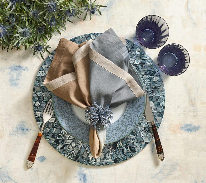 Inky blue and green rhombus-shaped capiz shells are hand-arranged in a striking mosaic place mat from Kim Seybert. It's beautifully coordinated with spatter blue rimmed plate and two-toned napkin held in place by a glass bead spray napkin ring.