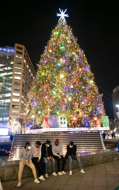 A group of young men sit beside the enormous Christmas tree n Campus Martius Park shortly after it was lit for the first time this season in Detroit Friday night. Although the 17th annual Detroit Tree Lighting event was a pre-recorded, made-for-TV event due to the coronavirus pandemic, the 19,000 lights on the official Detroit Christmas tree in Campus Martius Park were turned on Friday evening and many people enjoyed strolling around the park enjoying the lights and the unseasonably warm weather.