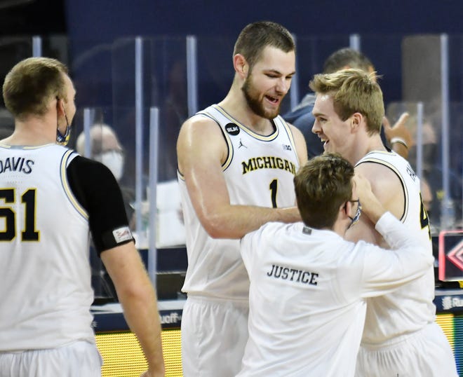 From left, Michigan's Austin Davis (51), Hunter Dickinson (1) and Luke Wilson (32) react with Jaron Faulds (44) after the win.  Michigan vs Ball State at Crisler Center in Ann Arbor, Mich. on Dec. 2, 2020.  Michigan wins, 84-65.