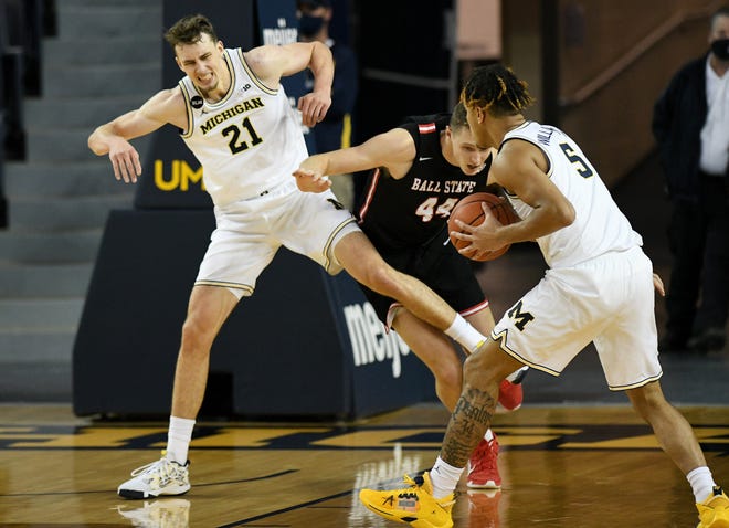 Michigan forward Terrance Williams II (5), right, watches as Michigan guard Franz Wagner (21) is in pain after this play with Ball State center Blake Huggins (44) in the second half.  Michigan vs Ball State at Crisler Center in Ann Arbor, Mich. on Dec. 2, 2020.  Michigan wins, 84-65.