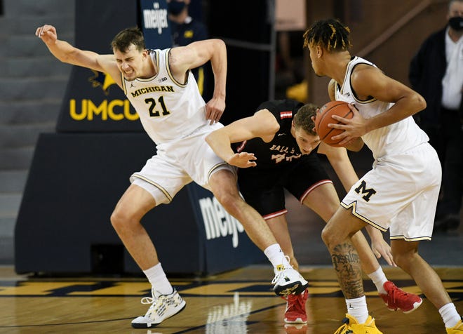 Michigan forward Terrance Williams II (5), right, watches as Michigan guard Franz Wagner (21) is in pain after this play with Ball State center Blake Huggins (44) in the second half.  Michigan vs Ball State at Crisler Center in Ann Arbor, Mich. on Dec. 2, 2020.  Michigan wins, 84-65.