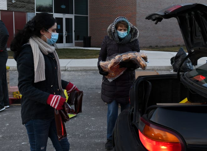 From left, Volunteers Maryam Saleem, 18, of Sterling Heights and Carole Hacker of Clinton Township load food into a trunk at the Forgotten Harvest mobile food pantry at the Sterling Heights Community Center in Sterling Heights, Mich. on Jan. 7, 2021.