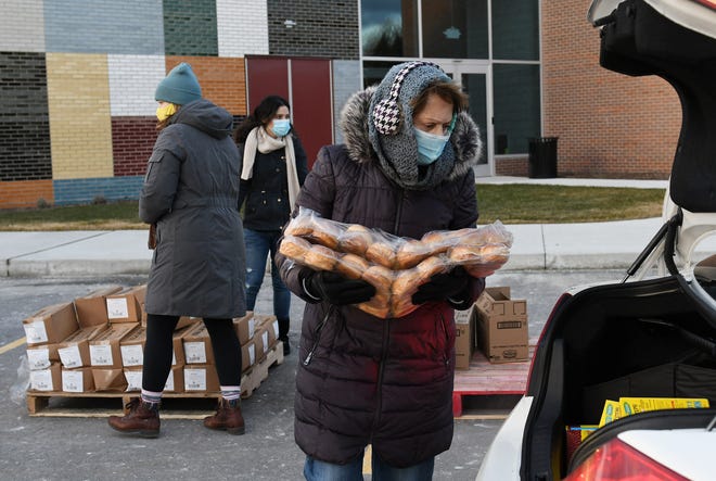 Volunteer Carole Hacker of Clinton Township loads buns into a trunk at the Forgotten Harvest mobile food pantry at the Sterling Heights Community Center in Sterling Heights, Mich. on Jan. 7, 2021.