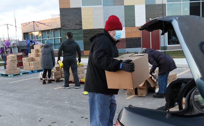 Volunteer Tony Rosales of Sterling Heights loads a box of food into a car at the Forgotten Harvest mobile food pantry at the Sterling Heights Community Center in Sterling Heights, Mich. on Jan. 7, 2021.