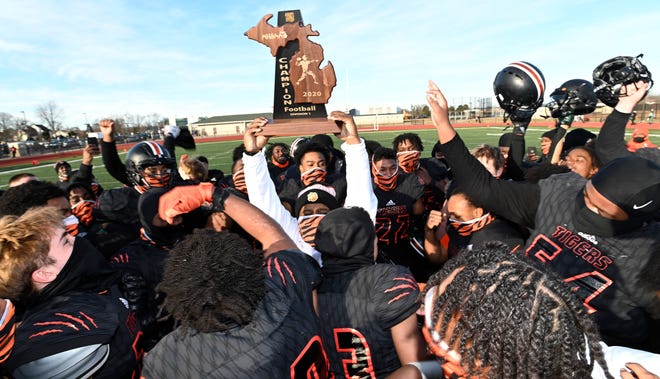 Head coach Jermain Crowell holds up his team's regional trophy after Belleville beat Detroit Cass Tech, 43-16, during an MHSAA Division 1 regional final, Saturday afternoon, Jan. 9, 2021, in Belleville.