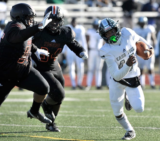 Cass Tech's Leeshaun Mumpfield (16) evades Belleville defenders as he scrambles due to receivers being covered in the first quarter.