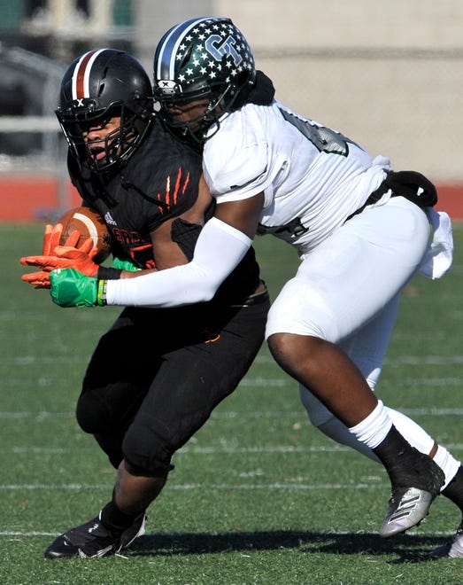Belleville's Davieon Pitchford (20) rushes as he's tackled by Cass Tech's Clarence Wilson (44) in the first quarter.
