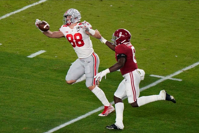 Ohio State tight end Jeremy Ruckert catches a pass in front of Alabama linebacker Christian Harris during the first half .