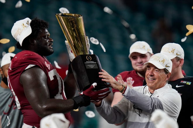 Alabama head coach Nick Saban and offensive lineman Alex Leatherwood hold the trophy after their win against Ohio State in an NCAA College Football Playoff national championship game, Tuesday, Jan. 12, 2021, in Miami Gardens, Fla. Alabama won 52-24.
