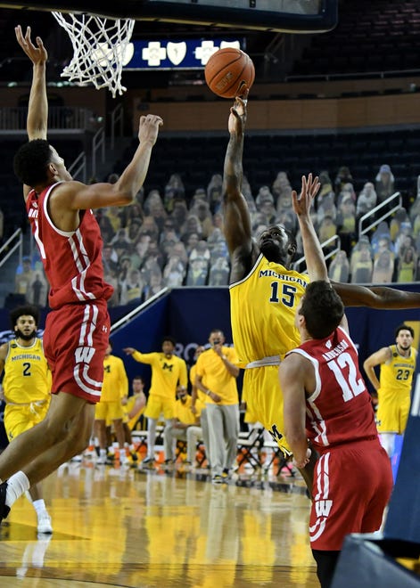Michigan guard Chaundee Brown (15) puts up a shot between Wisconsin guard Jonathan Davis (1) and Wisconsin guard Trevor Anderson (12) in the first half.