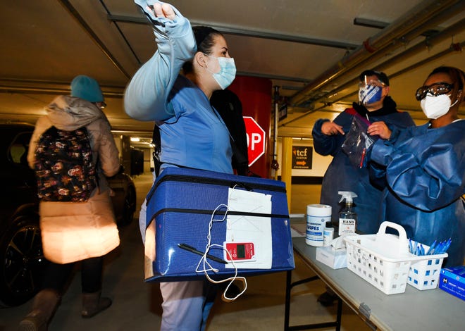 Meghan Boomhower with a cooler containing doses of vaccine at a COVID-19 vaccination drive-thru center at the TCF Center in Detroit on Wednesday.