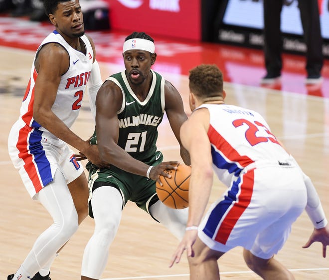 Bucks' Jrue Holiday looks for room around Pistons' l-r, Josh Jackson and Blake Griffin in the fourth quarter.