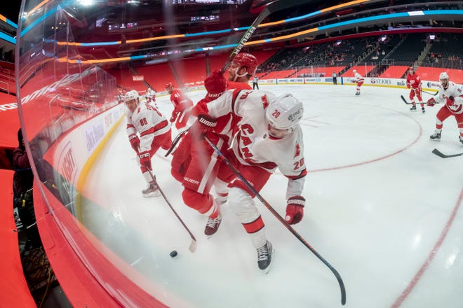 Detroit defenseman Patrik Nemeth and Carolina right wing Sebastian Aho battle for the puck in the second period during a game between the Detroit Red Wings and the Carolina Hurricanes, at Little Caesars Arena, in Detroit, January 14, 2021.