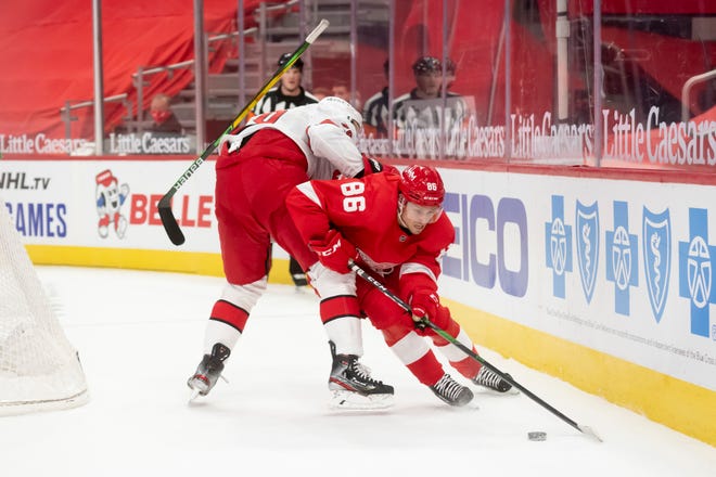 Carolina defenseman Brady Skjei loses his stick as Detroit left wing Mathias Brome plays the puck in the first period during a game between the Detroit Red Wings and the Carolina Hurricanes, at Little Caesars Arena, in Detroit, January 14, 2021.