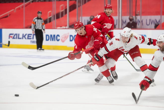 Detroit right wing Troy Stecher and Carolina center Ryan Dzingel battle for the puck in the third period during a game between the Detroit Red Wings and the Carolina Hurricanes, at Little Caesars Arena, in Detroit, January 14, 2021.