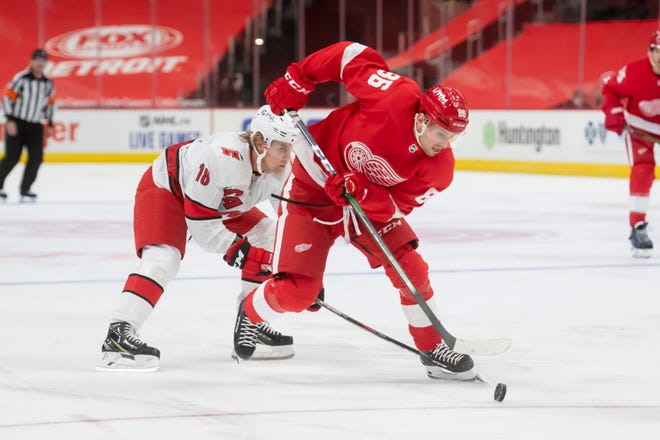 Detroit left wing Mathias Brome keeps the puck away from Carolina center Ryan Dzingel in the third period during a game between the Detroit Red Wings and the Carolina Hurricanes, at Little Caesars Arena, in Detroit, January 14, 2021.