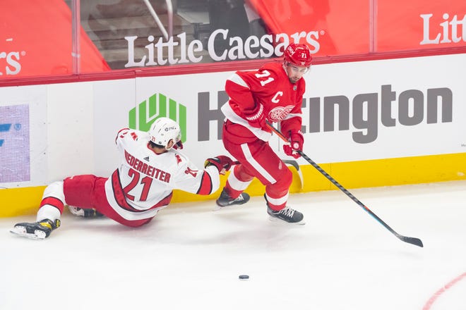 Detroit center Dylan Larkin slips past Carolina right wing Nino Niederreiter as he plays for the puck in the first period during a game between the Detroit Red Wings and the Carolina Hurricanes, at Little Caesars Arena, in Detroit, January 14, 2021.