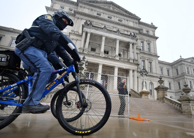 Michigan State Police patrol on bicycle the Michigan State Capitol, as security fencing is being erected in preparation for possible protests over the weekend in Lansing, Michigan  on January 15, 2021.