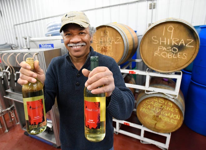 Black Fire Winery owner, winemaker and brewer Michael Wells with two of his wine creations 'Peachie' and 'A-Bell' in the winery/ brewery in Tecumseh, Michigan on February 11, 2021.