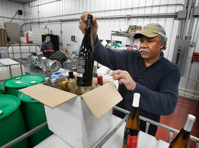 Black Fire Winery owner, winemaker and brewer Michael Wells pulls out some of his wine creations in the winery/ brewery in Tecumseh, Michigan on February 11, 2021.