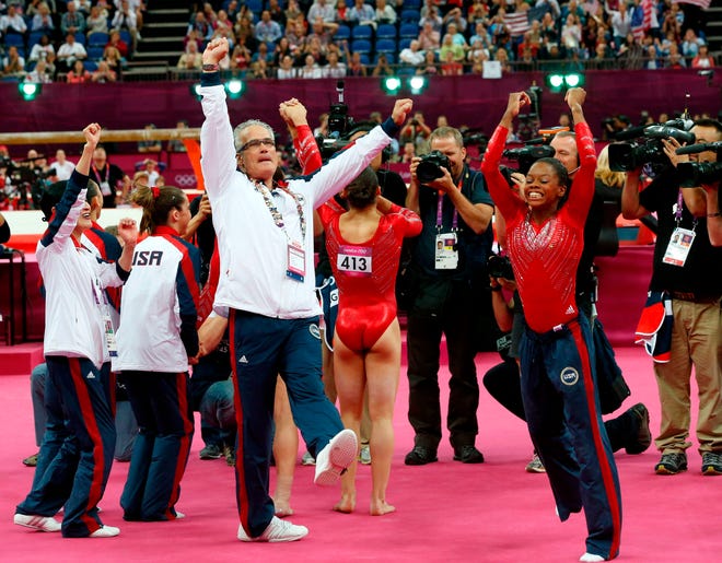 US gymnast Gabrielle Douglas (R), coach John Geddert celebrates with the rest of the team after the US  won gold in the women's team of the artistic gymnastics event of the London Olympic Games on July 31, 2012 at the 02 North Greenwich Arena in London. Team US won gold, Team Russia took silver and Team Romania got bronze.