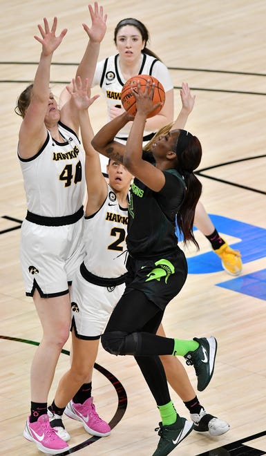 Michigan State guard Nia Clouden (24) puts up a shot over Iowa's Sharon Goodman (40) and Gabbie Marshall (24) in the first half.