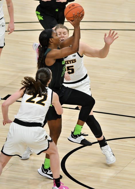 Michigan State guard Nia Clouden (24) drives between Iowa's Monika Czinano (25) and Caitlin Clark (22) in the second half.