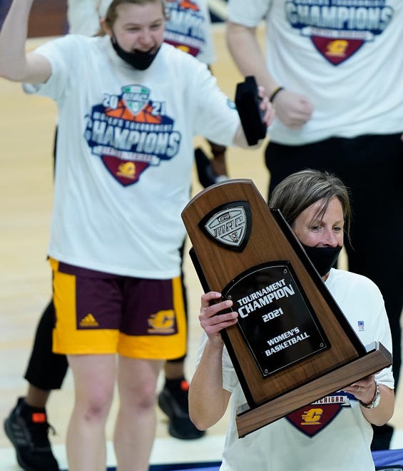 Central Michigan's head coach Heather Oesterle holds up the MAC tournament championship trophy.