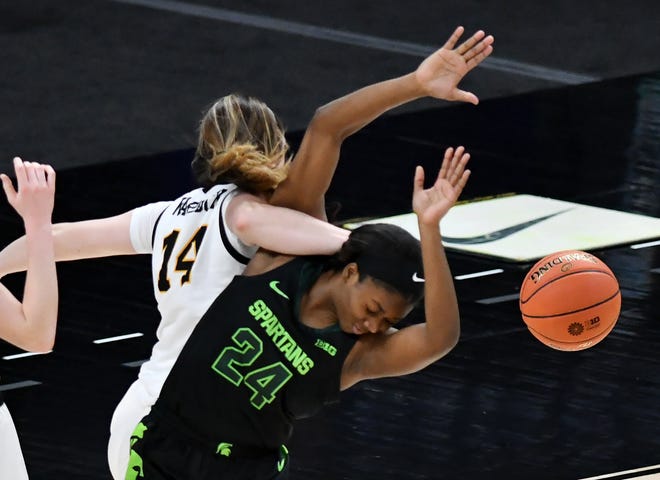 Michigan State guard Nia Clouden (24) and Iowa guard McKenna Warnock (14) tangle up in the second half.  Michigan State vs Iowa in the Big Ten Women's Basketball Tournament semifinal at Bankers Life Fieldhouse in Indianapolis, Ind. on Mar. 12, 2021. Iowa wins, 87-72.