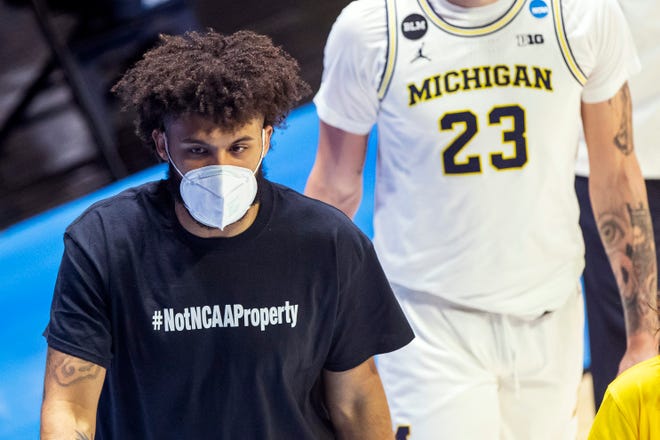 Michigan's Isaiah Livers wears a T-shirt that reads "#NotNCAAProperty" as he walks off the court with teammates after the first half.