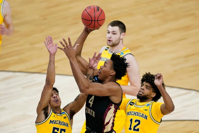 Florida State guard Scottie Barnes, center, shoots over Michigan guard Eli Brooks, left, and guard Mike Smith, right, during the first half.
