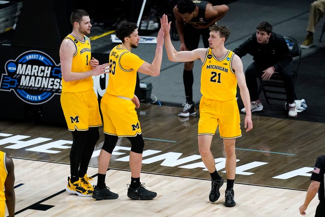 Michigan guard Franz Wagner (21) celebrates with teammates center Hunter Dickinson (1) and forward Brandon Johns Jr. (23) after making a basket during the first half.