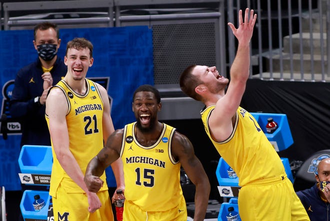 Michigan players, from left, Franz Wagner, Chaundee Brown and Hunter Dickinson celebrate their 76-58 Sweet Sixteen victory over Florida State at Bankers Life Fieldhouse on March 28, 2021 in Indianapolis, Indiana. Michigan now advances to the Elite Eight.