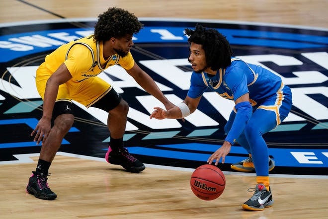UCLA guard Tyger Campbell, right, drives past Michigan guard Mike Smith, left, during the first half.