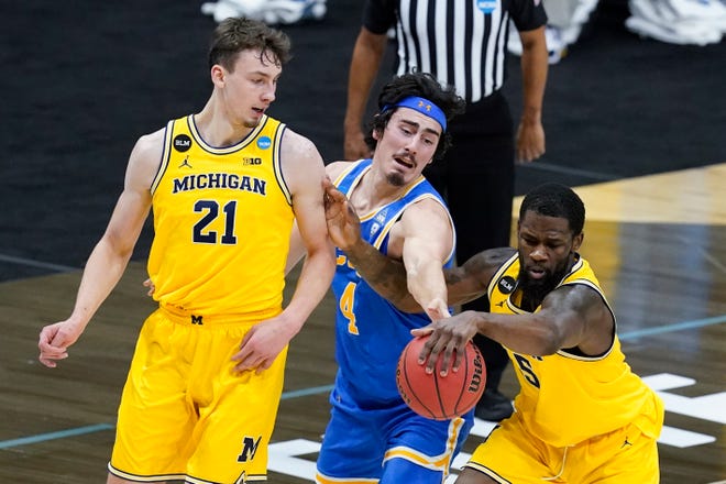 UCLA Bruins guard Jaime Jaquez Jr. (4) and Michigan guard Chaundee Brown (15) battle for a loose ball as Franz Wagner (21) looks on during the first half.