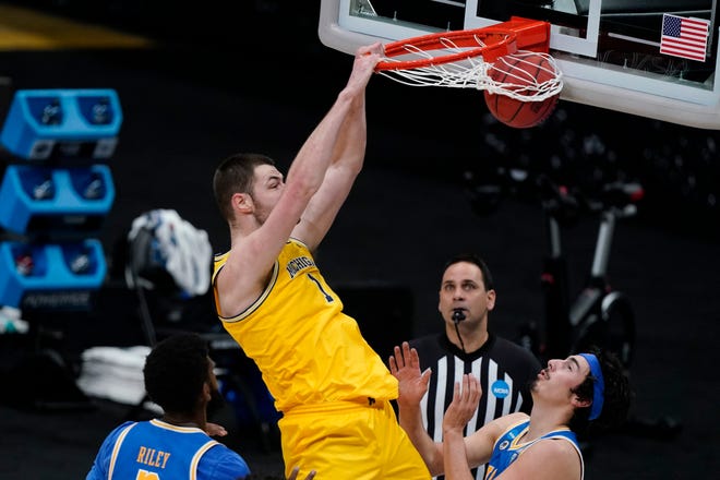 Michigan center Hunter Dickinson (1) dunks the ball over UCLA forward Cody Riley, left, and guard Jaime Jaquez Jr., right, during the first half.