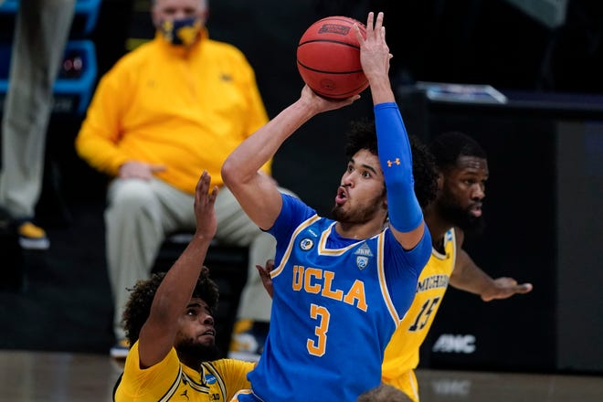 UCLA guard Johnny Juzang (3) shoots over Michigan guard Mike Smith, left, during the first half.
