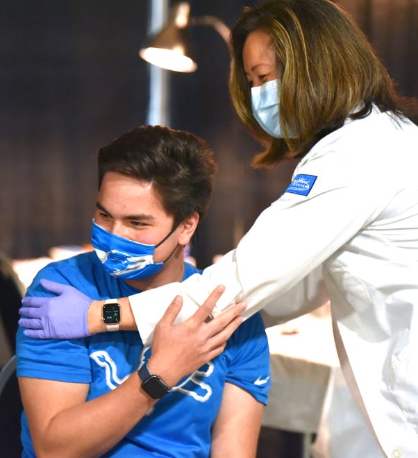 Protect Michigan Commission COVID-19 student ambassador volunteer Aidan Shoresh gets a hug from his mother, Dr. Betty Chu, VP and associate chief clinical officer, chief quality officer for Henry Ford Health System, after she gives him the vaccination.