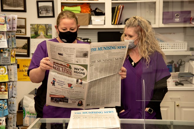 Inside Putvin's Drugstore in Munising on Wednesday, March 31, 2021, Crystal Cota, left, and Carla Erickson read the "Memories" section in the final edition of The Munising News. The final edition included a farewell message from newspaper owners Willie and Nancy Peterson and a reproduction of the front page of the first edition of the paper, published on Feb. 13, 1896.
