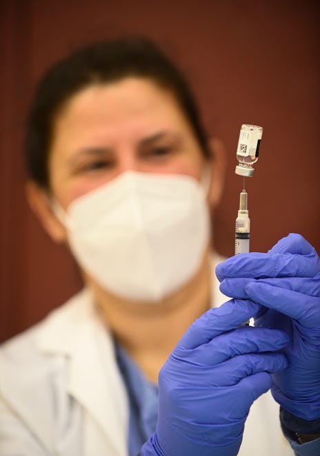 Pharmacist Nabilah Seblini fills a syringe with the Johnson & Johnson vaccine during a vaccination clinic at Western International High School in Detroit.