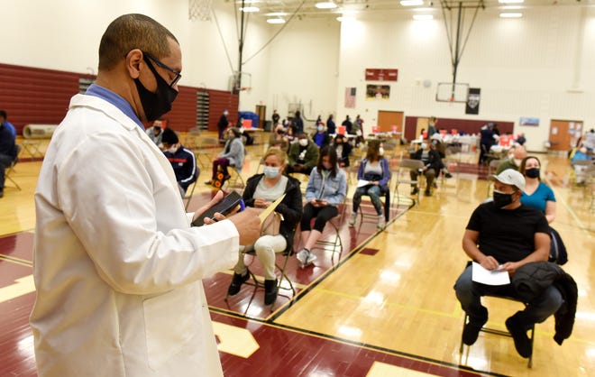 Dr. Vincent Trent keeps watch over vaccinated clients for 15 minutes to make sure no one has an adverse reaction, during a vaccination clinic at Western International High School in Detroit, Monday, April, 12, 2021.