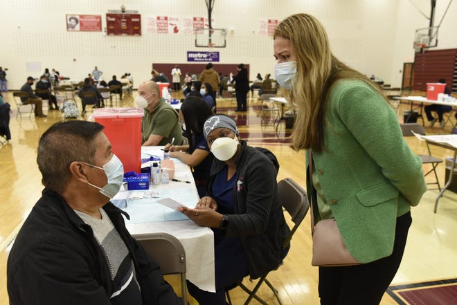 Translator Jenny Beaver, right, asks a question of Raul Zamora Martinez, left, for LaToya Edwards, LPN, center, during a vaccination clinic at Western International High School in Detroit, Monday, April, 12, 2021.