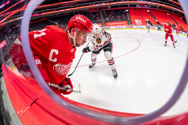 Detroit center Dylan Larkin and Chicago left wing Brandon Hagel battle along the boards in the third period during a game between the Detroit Red Wings and the Chicago Blackhawks, at Little Caesars Arena, in Detroit, April 15, 2021.