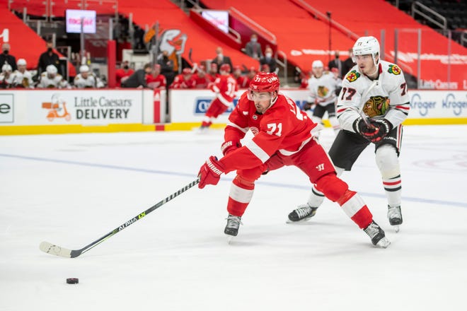 Detroit center Dylan Larkin keeps the puck away from Chicago center Kirby Dach in the first period.
